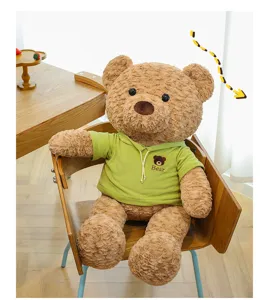 Vista detallada de un gran oso de peluche marrón con sudadera verde en una silla de madera