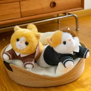 Adorable plush cat toy dolls wearing knitted sweaters lying in a cozy woven round pet bed.