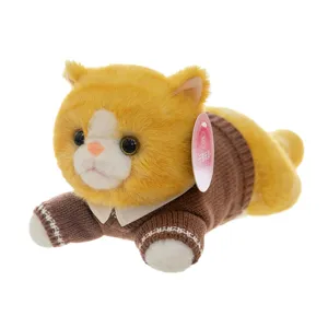 Cute orange and white plush toy cat wearing a brown knitted sweater in lying pose