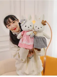 Close-up of two adorable white plush rabbits dressed in charming pink and grey outfits.