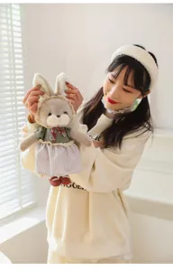 Detail view of a model holding a plush rabbit toy wearing a vintage style dress