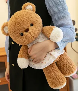 Detail eines weichen braunen Teddybären in einem Blumenkleid, der gehalten wird