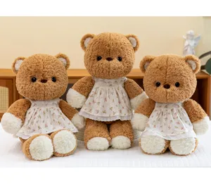 Drei braune Teddybären aus Plüsch in eleganten weißen Blumenkleidern mit Spitzenbesatz.