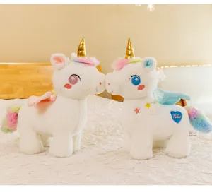 Primo piano di due peluche a forma di unicorno bianco con corna dorate sul letto