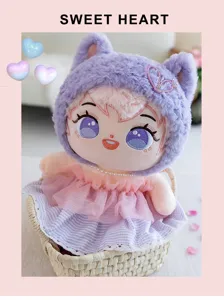Vista detallada de una dulce muñeca de algodón de peluche con gorro morado y vestido rosa