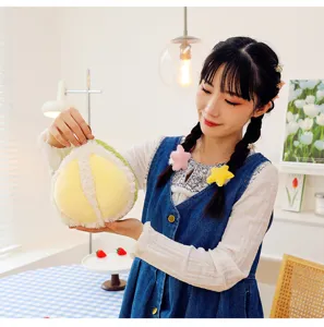 Primo piano di un morbido peluche a forma di frutta tenuto da una modella in un interno
