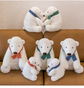 Group of white polar bear plush toys with colorful plaid scarves on a leather sofa
