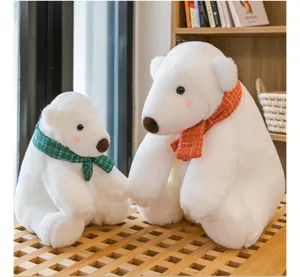 Two white polar bear plush toys with scarves of different sizes in a home setting