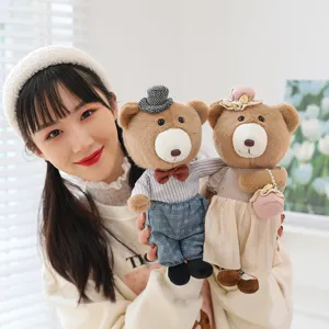 Adorable couple teddy bear plush toys in stylish outfits being held by a smiling model.