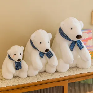 Set of three soft white polar bear plush toys with blue scarves shown on wooden cabinet