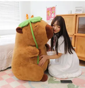 Grande peluche capibara morbido con foglia di loto verde abbracciato da una ragazza in camera
