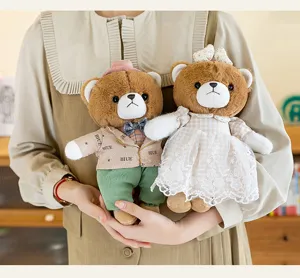 Primer plano de dos adorables ositos de peluche vestidos sostenidos por una persona
