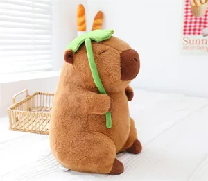 Dettaglio di un peluche di capibara con una foglia di loto verde su uno sfondo bianco