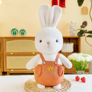 Schattig wit pluche konijn in een oranje overall met lentezon borduurwerk detail