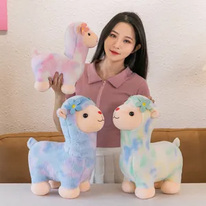 Cute rainbow alpaca plush toy with colorful tie-dye fur and sweet floral decoration.
