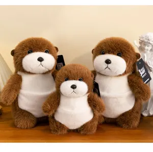 Three cute sea otter plush toys in various sizes displayed on a wooden desk with a statue