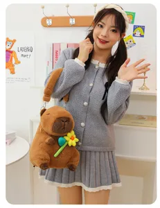Cute brown capybara plush backpack held by a model in a cozy indoor setting