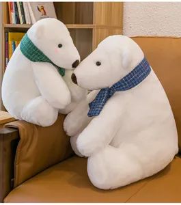 Close-up of two white plush polar bears with green and blue scarves on a chair