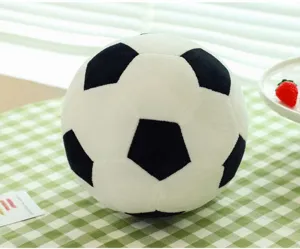 Close-up of a soft black and white plush soccer ball pillow on a green checkered table.