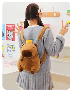 Adorable plush capybara backpack with orange detail shown being worn in a cozy room