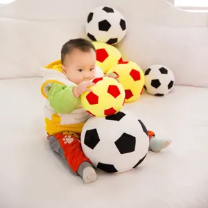 Soft plush soccer ball toy pillows in various colors shown with a cute baby in a home setting