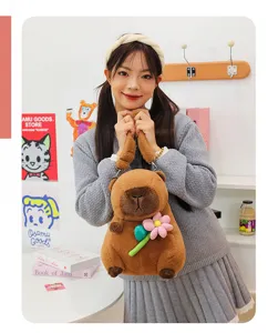 Adorable soft plush brown capybara backpack held by a model in a cozy indoor studio