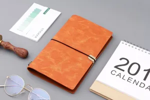 Detailansicht eines orangefarbenen Vintage-Notizbuchs A6 aus Kunstleder mit Bandverschluss