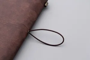 Makro-Detail eines braunen Vintage-Notizbuchs aus Kunstleder mit Gummiband-Verschluss.