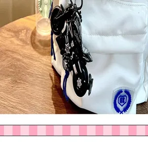 Gros plan d'un porte-clés moto en alliage noir suspendu à un sac à dos blanc moderne.