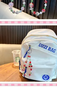 Close-up of a colorful handmade cherry beaded charm with rhinestones on a white backpack