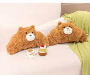 Detalle de peluches de oso en forma de cruasán sobre un cómodo sofá blanco con decoración