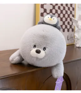 Adorable y suave león marino de peluche gris con un pequeño pingüino, vista detallada