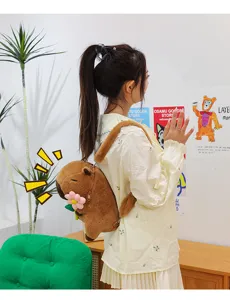 Brown plush capybara backpack featuring flower detail and adjustable straps worn by model