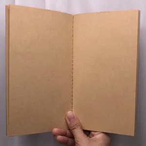 Close-up detail view of a vintage kraft paper notebook with visible center stitching.