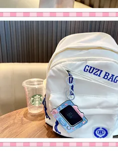 Detail view of a mini pig-shaped writing board keychain hanging on a white backpack