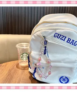 Detail of handmade beaded flower charm featuring pink and blue beads attached to a white backpack.
