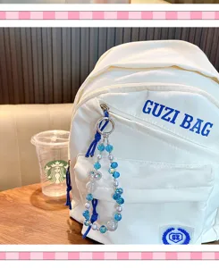 Detailed macro view of a blue crystal heart beaded charm on a white fabric backpack