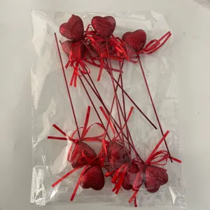 Close-up of red glitter heart picks with ribbons inside a clear plastic storage bag.