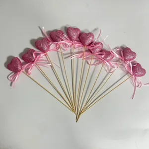 Fanned arrangement of pink glitter foam heart picks with satin bows for wedding decor.