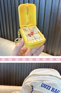 Detailed close-up showing a yellow electric maze game keychain attached to a white backpack