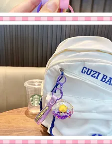 Schalenförmiger Acryl-Schlüsselanhänger mit gelber Ente an einem weißen Rucksack