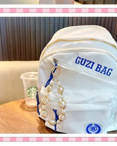 Porte-clés élégant en perles avec étoiles dorées suspendu à un sac à dos blanc tendance