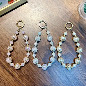 Trois porte-clés en perles faits main avec breloques étoiles sur fond de bois naturel
