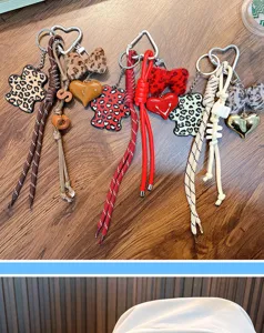 Detail view of leopard print bear and heart charms with braided rope keychains on wood.