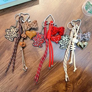 Leopard print bear keychains with heart and bow charms displayed on wooden background