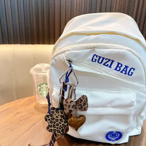 Stylish leopard print plush bear and bow bag charm accessories on a white backpack lifestyle view