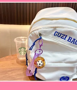 Close-up of sports football liquid quicksand keychain hanging on a white backpack