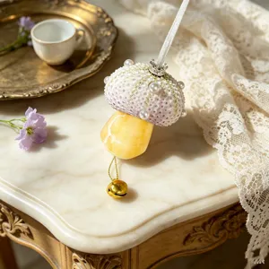 Close-up of handmade sea urchin shell mushroom ornament featuring pearls and gold bell