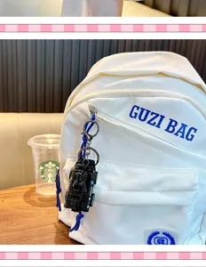 Close-up detail of a black police car model keychain attached to a white backpack zipper