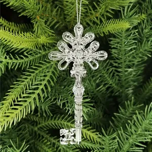 Macro detail of transparent acrylic Christmas key ornament hanging on green pine branch.
